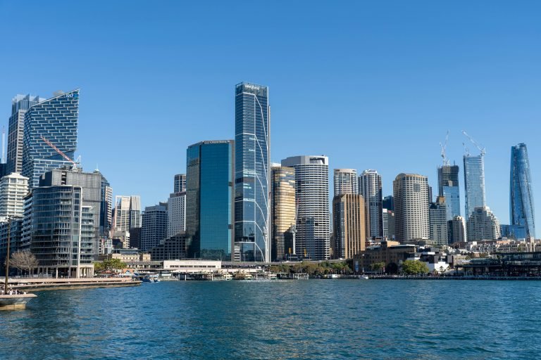 Sydney skyline viewed from the harbour, showing modern skyscrapers along the waterfront on a clear day.