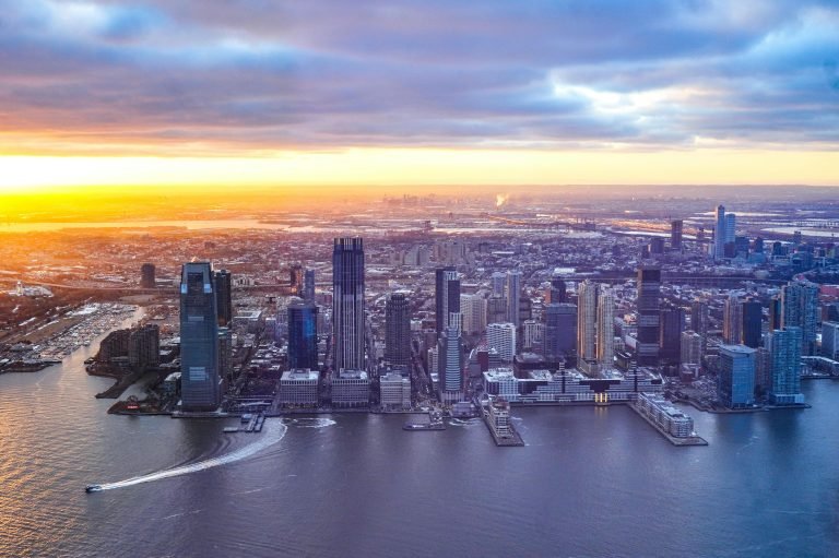 Aerial view of Sydney skyline at sunset, with waterfront neighbourhoods and harbour pathways visible along the shore.
