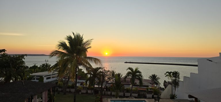 Coucher de soleil sur l’océan à Madagascar avec palmiers et maisons en bord de mer
