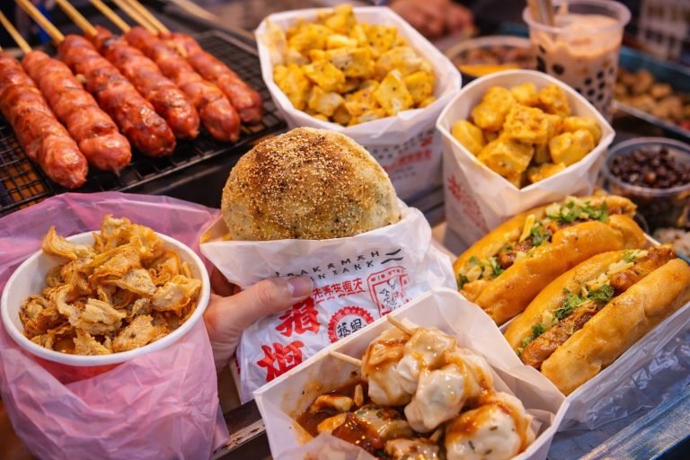 Raohe night market street food including black pepper pork buns, grilled sausages, dumplings, fried snacks, and bubble tea in Taipei