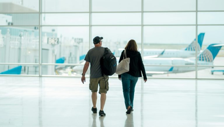 Couple walking through airport terminal illustrating credit-card-travel-insurance-vs-travel-insurance for international travel protection