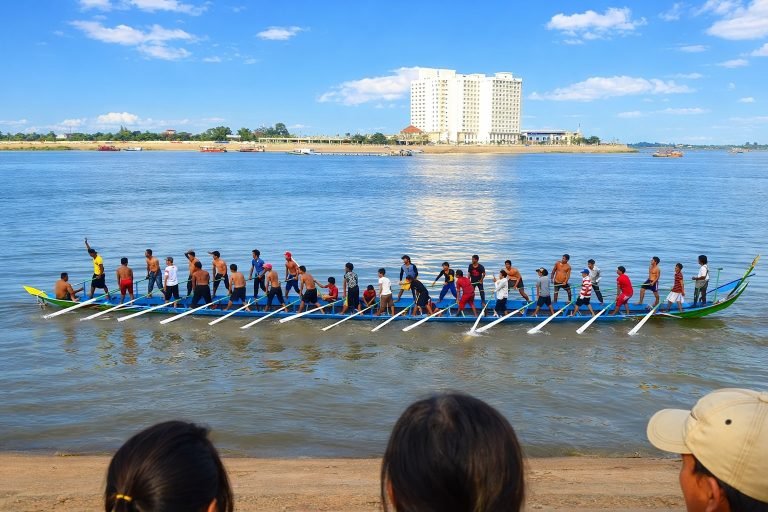 Cambodia water festival boat race with longboat rowers on a sunny day under blue skies in Phnom Penh