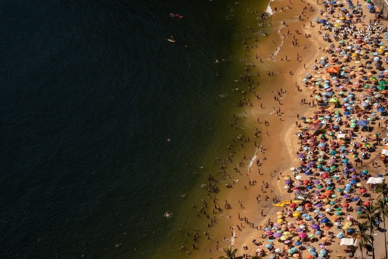 Best areas to stay in Rio de Janeiro – aerial view of Copacabana beach with colorful umbrellas and crowds Caption Description