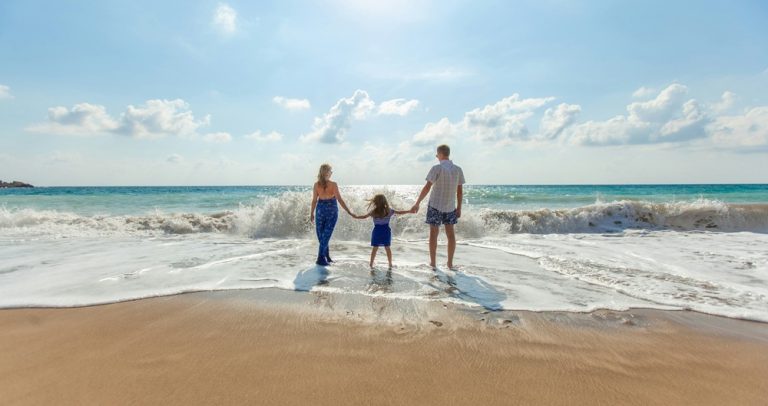 Family walking into ocean illustrating credit-card-travel-insurance-vs-travel-insurance for international family travel