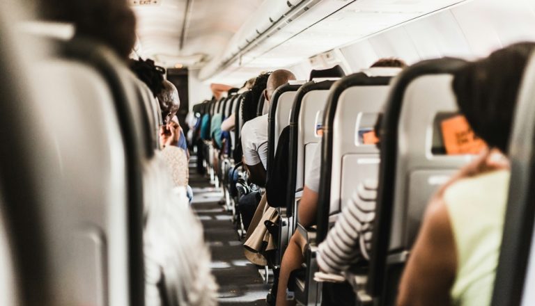 Passengers seated on airplane illustrating credit-card-travel-insurance-vs-travel-insurance during international travel