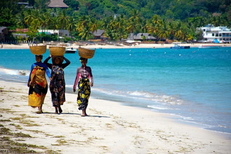Madagascar beach scene with local women carrying baskets along the coastline in a tropical setting