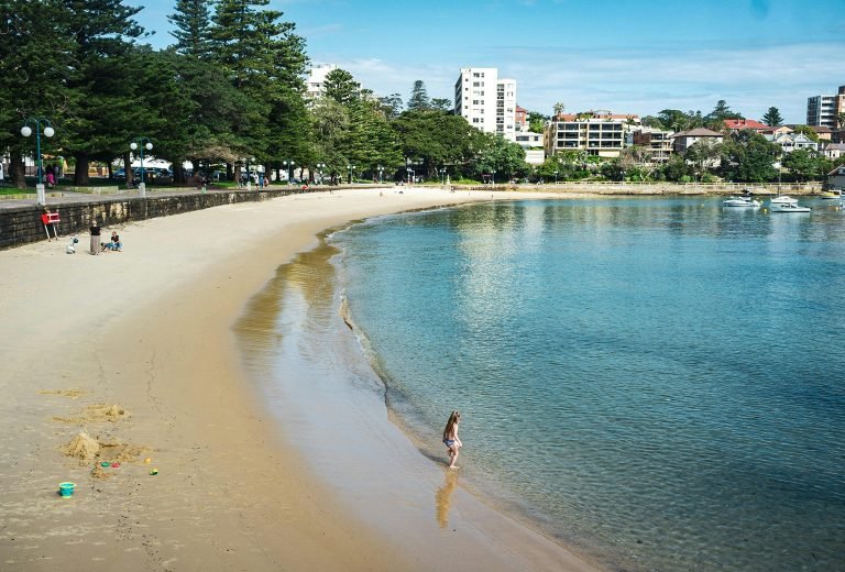 Manly Beach Sydney coastline with calm water, one of the best areas to stay in Sydney for a relaxed coastal escape Caption: Description: