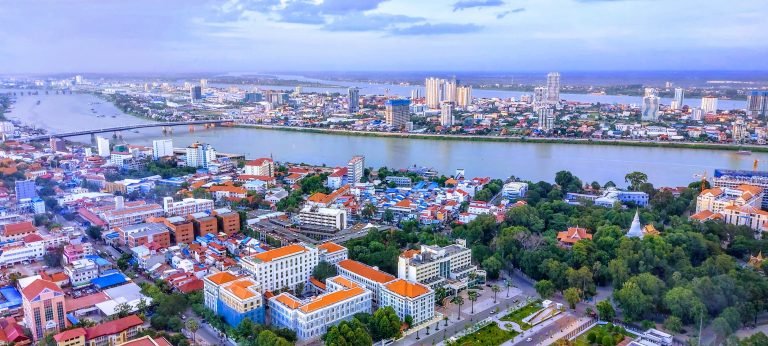 Things to do in Cambodia: aerial view of Phnom Penh skyline with Tonle Bassac River, city buildings, and green park areas