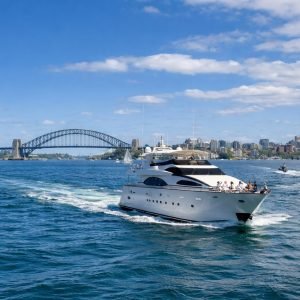 Sydney Harbour Cruises luxury yacht sailing past Harbour Bridge on a sunny afternoon with blue skies