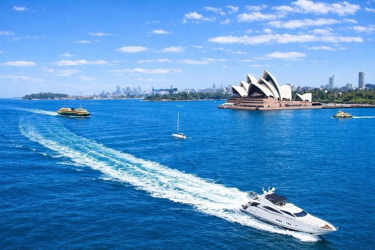 Sydney Harbour Cruises - Yacht near Opera House on a bright sunny day with blue skies and blue water