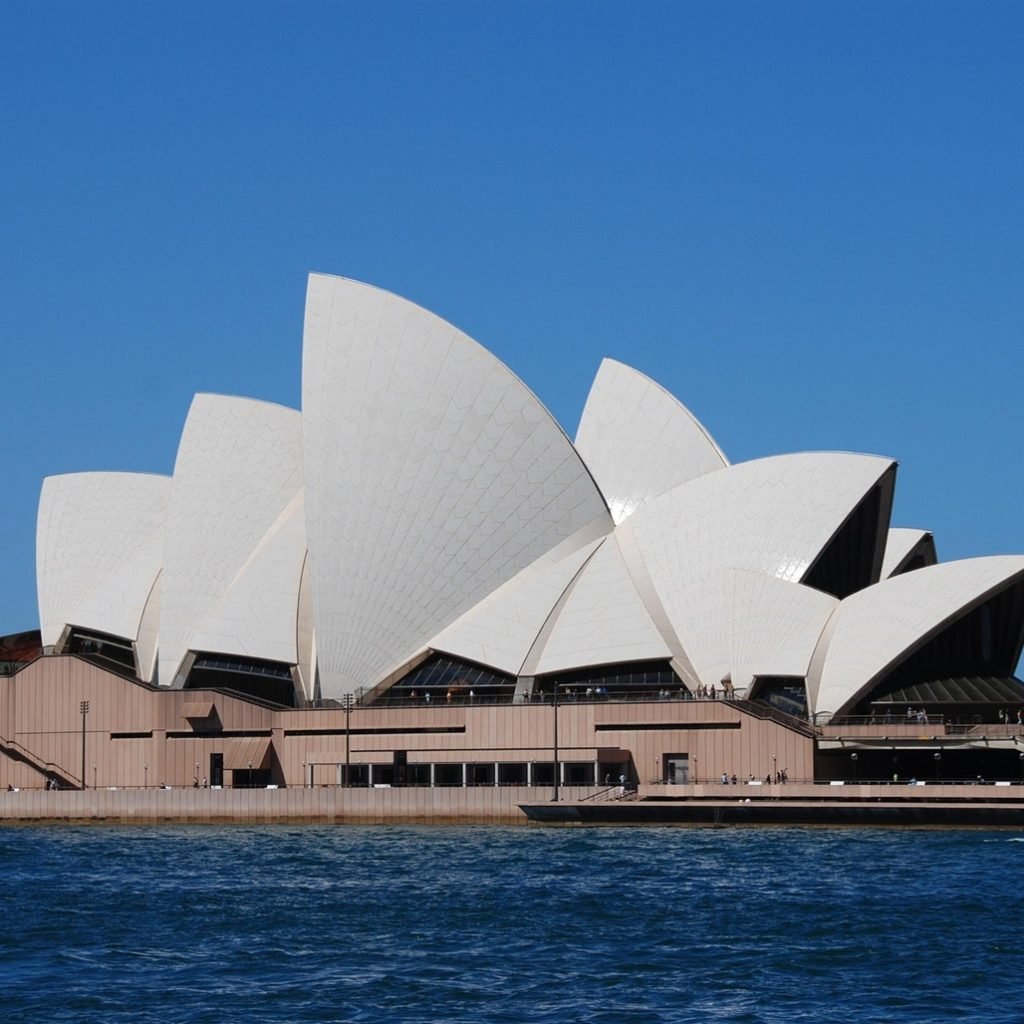 Sydney Opera House view from the harbour with blue sky, public transport in Sydney using Opal card Sydney system nearby