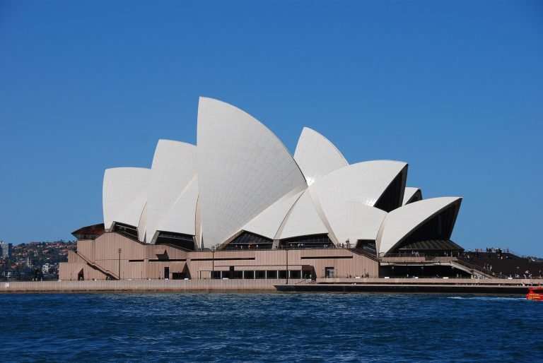 Sydney Opera House view from the harbour with blue sky, public transport in Sydney using Opal card Sydney system nearby