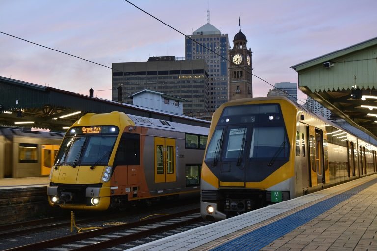 Sydney Airport Transport trains at Central Station platform with city skyline and clock tower in the background