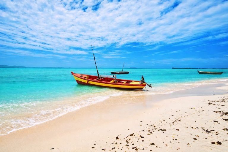 Colorful yellow and red fishing boat on a Madagascar beach with turquoise water