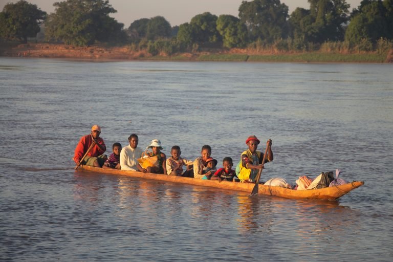 Local family traveling by wooden canoe on a river in rural Madagascar