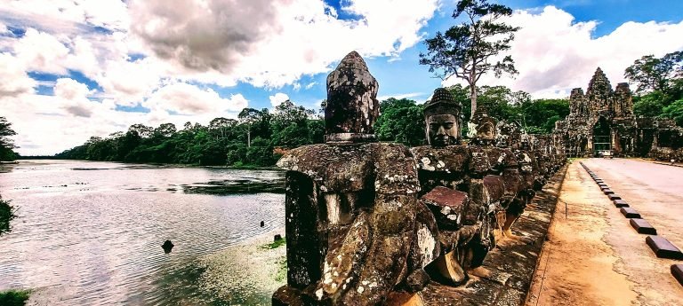Angkor Thom South Gate causeway with stone guardian statues lining bridge over moat in Angkor Cambodia