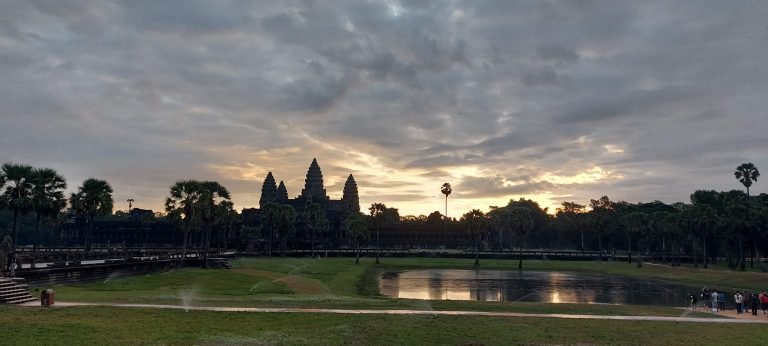 Angkor Wat Guide showing Angkor Wat at sunrise with temple silhouette and reflection pond in Siem Reap Cambodia
