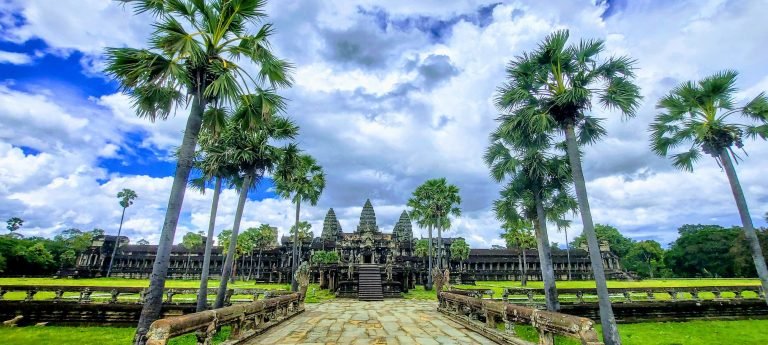 Things to do in Siem Reap include visiting Angkor Wat temple with palm trees and a dramatic sky surrounding the iconic ancient complex