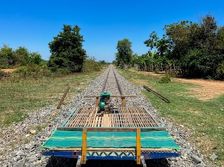 Bamboo train ride along railway tracks in Battambang Cambodia through rural countryside under blue skies