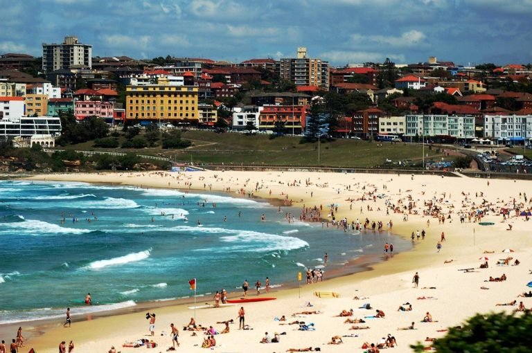 Sydney travel tips: Bondi Beach with people, waves, and coastal neighborhood in Sydney