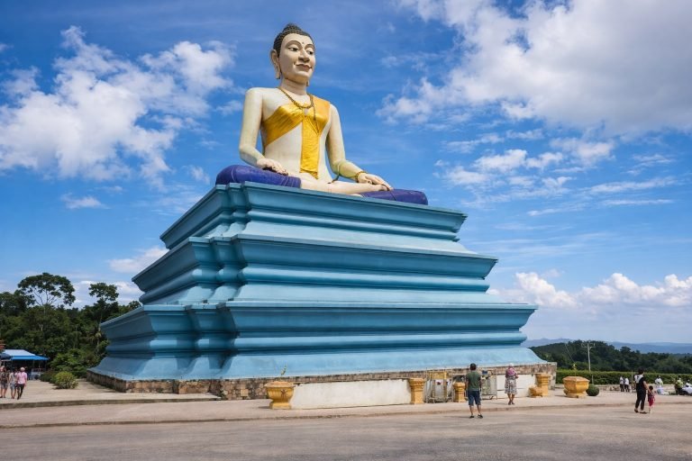Things to do in Kampot - Large Buddha statue on blue pedestal with clear sky