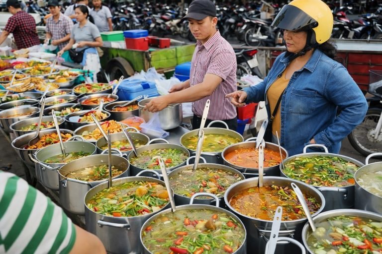 Cambodian food street market with multiple pots of soups and local dishes being served in a busy outdoor setting
