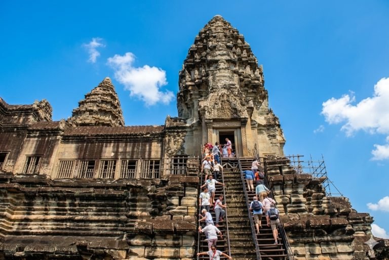 Tourists climbing steep stairs of Angkor Wat temple tower in Siem Reap Cambodia