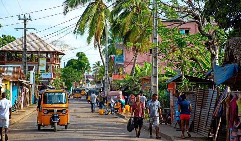 daily life in madagascar street scene with tuk tuk pedestrians and local shops Caption: Description: