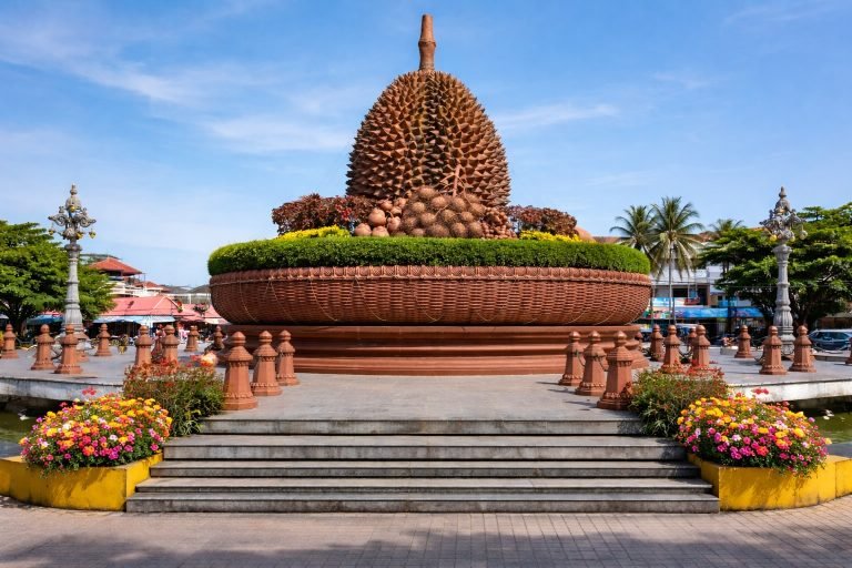 Things to do in Kampot - Durian statue landmark roundabout with tropical plants and blue sky