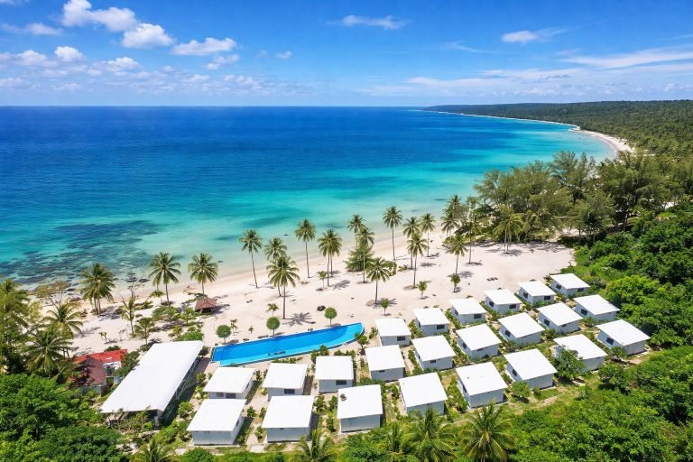 Koh Rong resort with white sandy beach, palm trees, and azure blue water on a sunny tropical day
