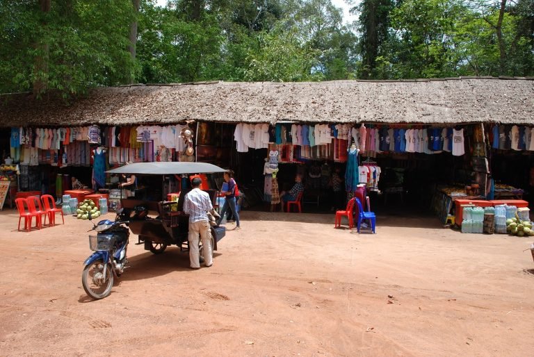 local market near Angkor Wat with souvenir stalls clothing drinks and tuk tuk in Siem Reap Cambodia Caption Description