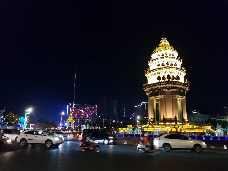 Getting around Cambodia at night near Phnom Penh Independence Monument with traffic and motorbikes Caption: Description: