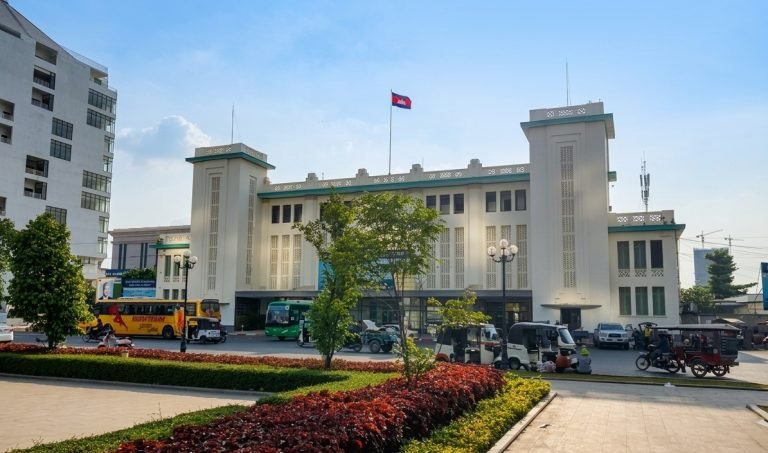 Phnom Penh train station building with buses, tuk-tuks, and local traffic