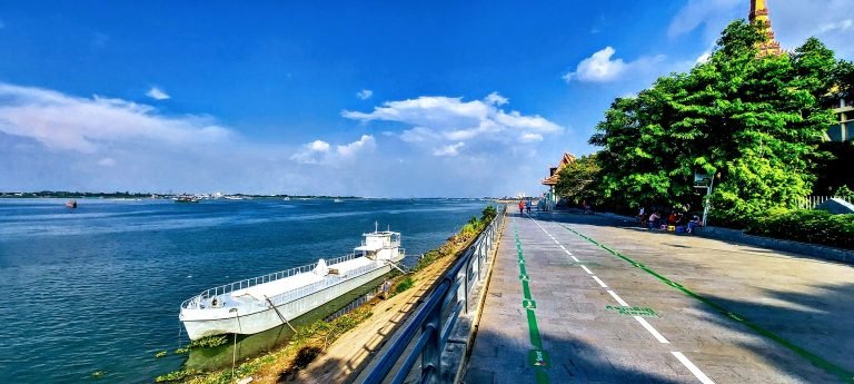 Riverside walkway along the Mekong River in Phnom Penh with boats and pedestrians