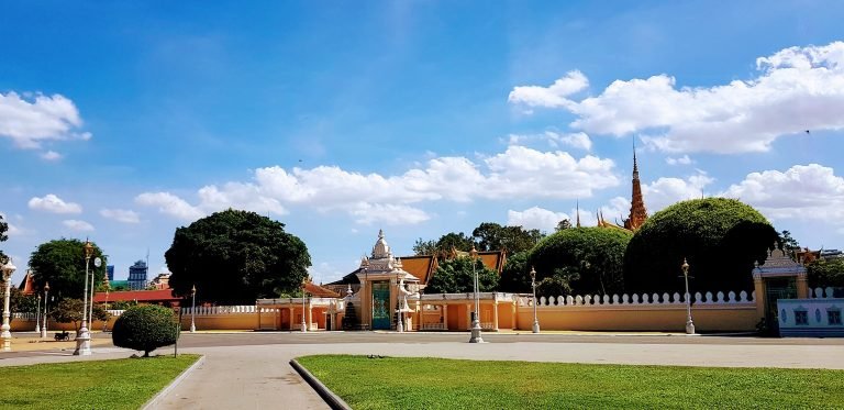 Entrance gate of the Royal Palace in Phnom Penh with traditional Khmer architecture, manicured gardens, and blue sky