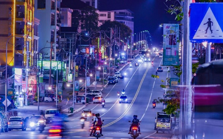 Sihanoukville Cambodia city street at night with traffic, neon lights, and modern road infrastructure Caption: Description: