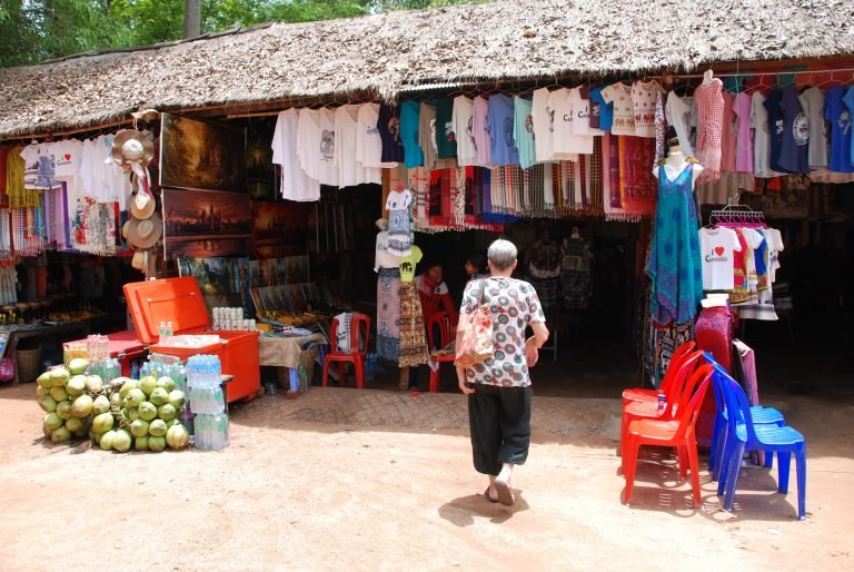 souvenir market stall near Angkor Wat selling t-shirts scarves paintings and coconuts in Siem Reap Cambodia