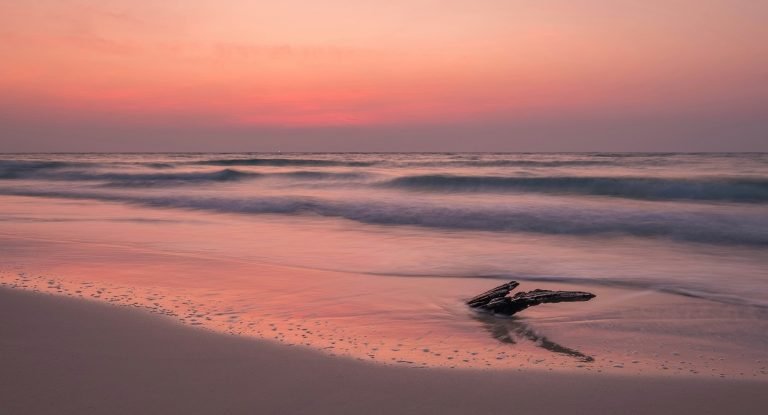 Sunset on Koh Rong beach with gentle waves, soft sand, and pink sky over the ocean Caption: Description:
