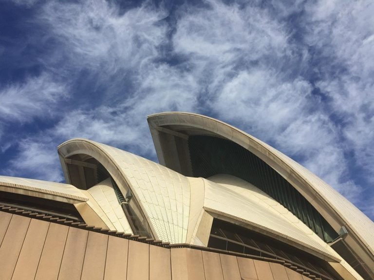 Sydney travel tips: close-up view of Sydney Opera House architecture against blue sky 📝 Caption 📄 Description