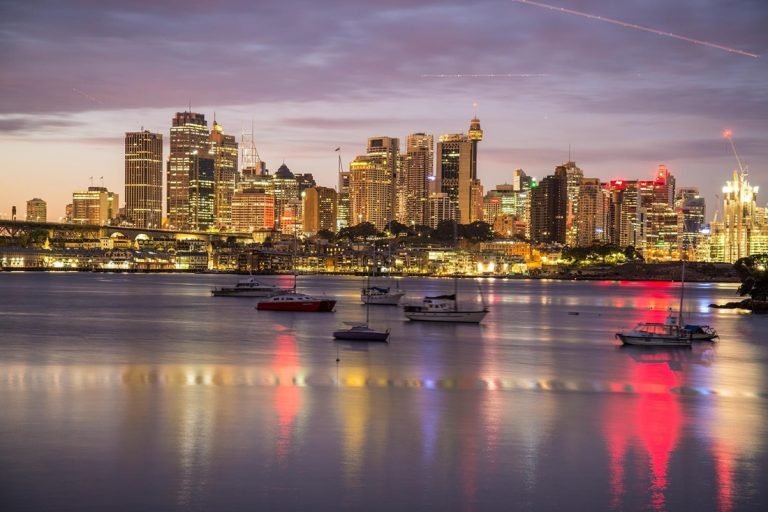 Sydney travel tips: Sydney skyline at night with harbour reflections and boats