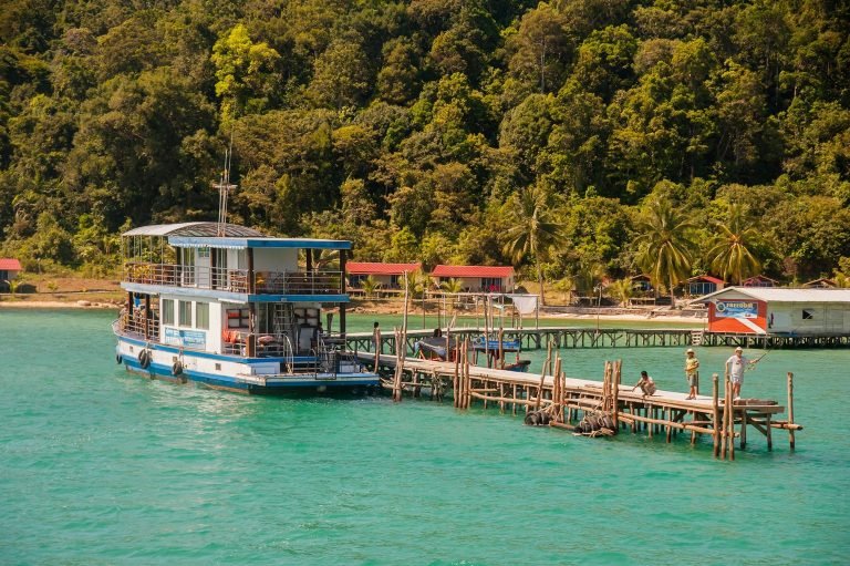 Boat arriving at pier on Koh Rong samloem with wooden jetty and turquoise water along the island coast Caption: Description: