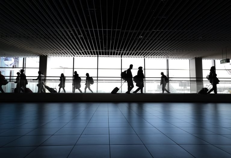 Passengers walking through airport terminal with luggage heading to catch flights
