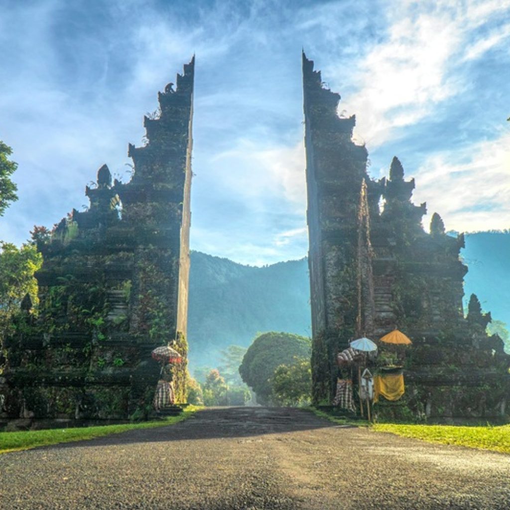 Ancient Balinese temple gate surrounded by lush mountains and greenery, illustrating important Bali travel tips for cultural sightseeing and respectful temple visits