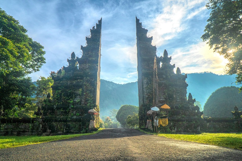 Ancient Balinese temple gate surrounded by lush mountains and greenery, illustrating important Bali travel tips for cultural sightseeing and respectful temple visits