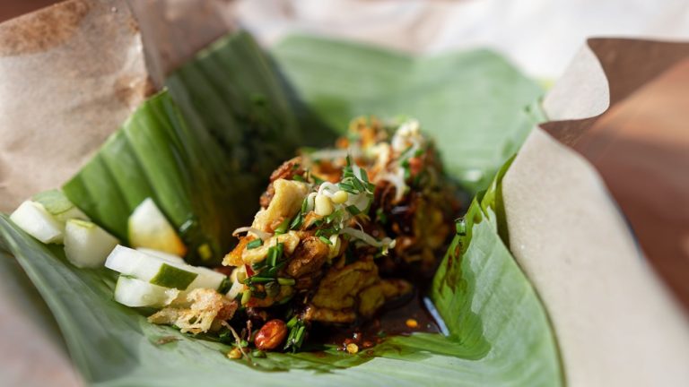Bali travel cost guide featuring traditional Indonesian nasi pecel with vegetables and peanut sauce wrapped in banana leaves