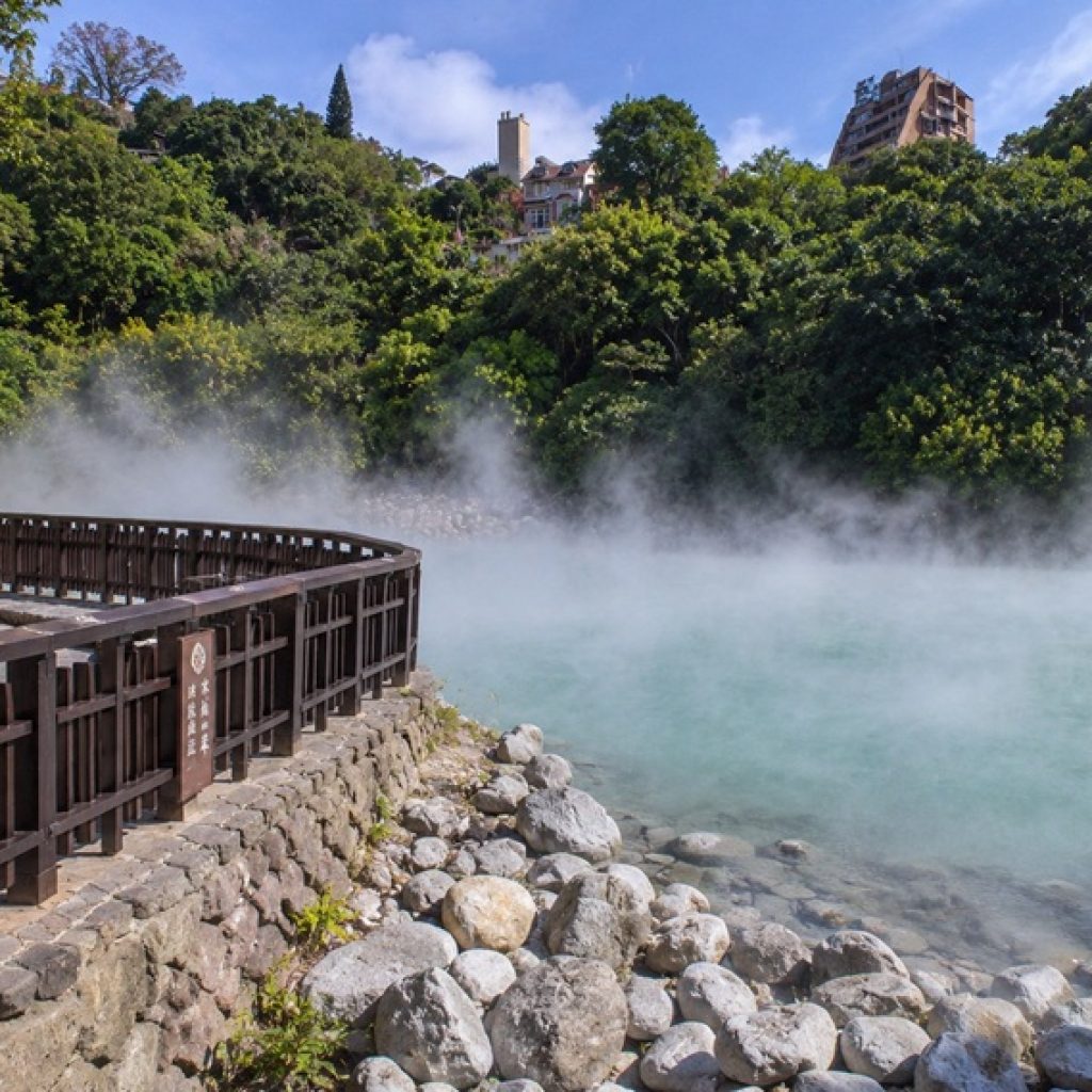 Taiwan hot springs at Beitou in Taipei with turquoise steaming water, wooden walkway, rocks, and lush green hillside