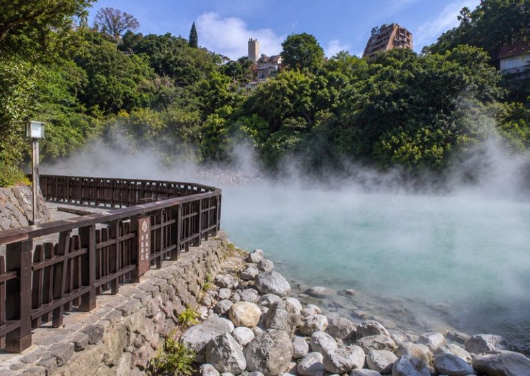 Taiwan hot springs at Beitou in Taipei with turquoise steaming water, wooden walkway, rocks, and lush green hillside