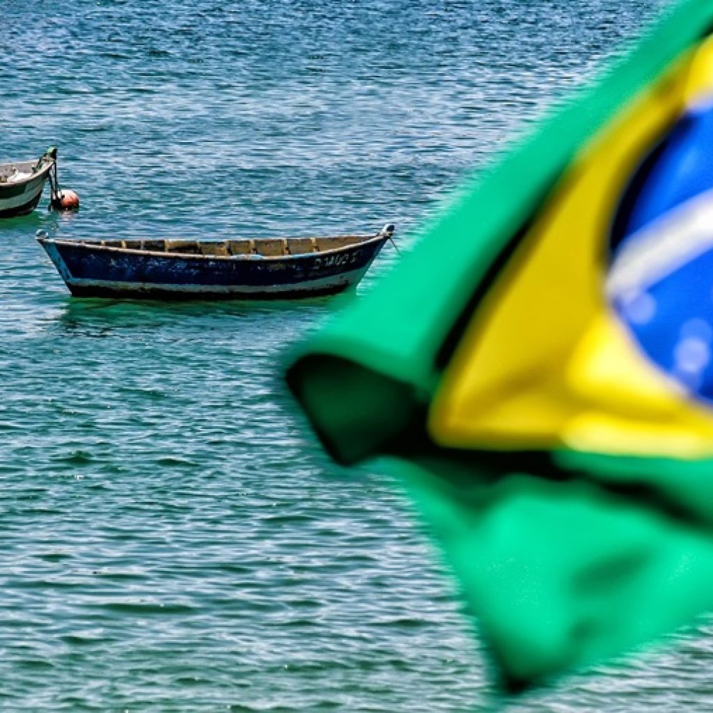 Brazilian flag overlooking coastal waters and fishing boats representing the best islands in Brazil