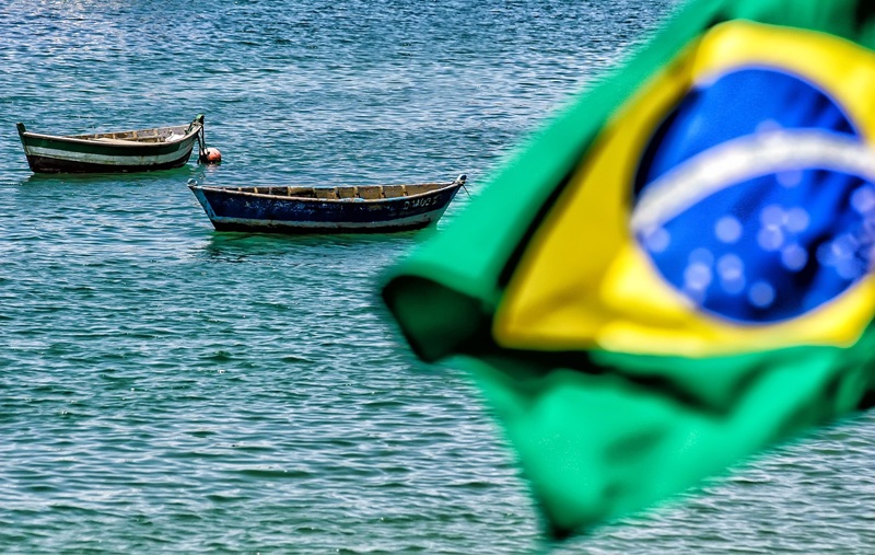 Brazilian flag overlooking coastal waters and fishing boats representing the best islands in Brazil