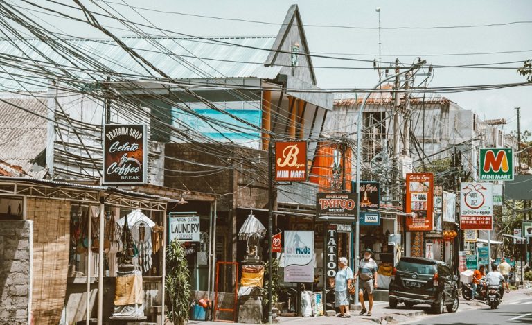 Local street lined with small shops, cafés, tattoo studios, and businesses in Bali